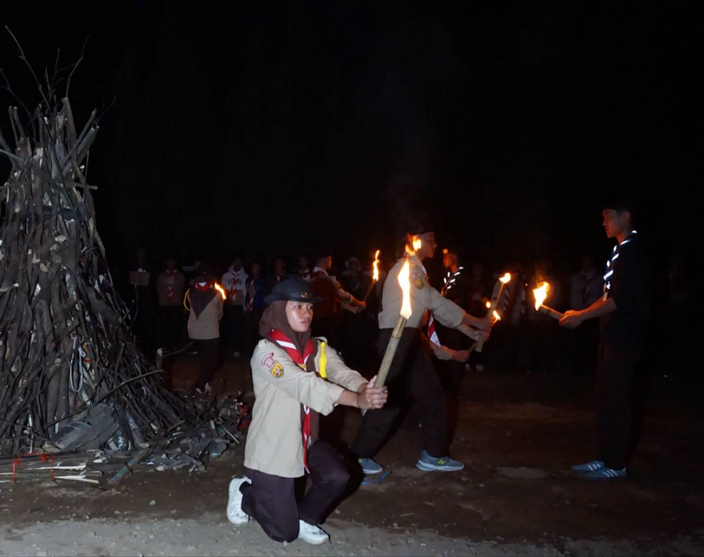 Peserta pramuka membawa obor dalam prosesi penyalaan api unggun di kegiatan Malam Puncak PTA-Bantara SMK Al-Ma’shum Mardiyah malam hari.