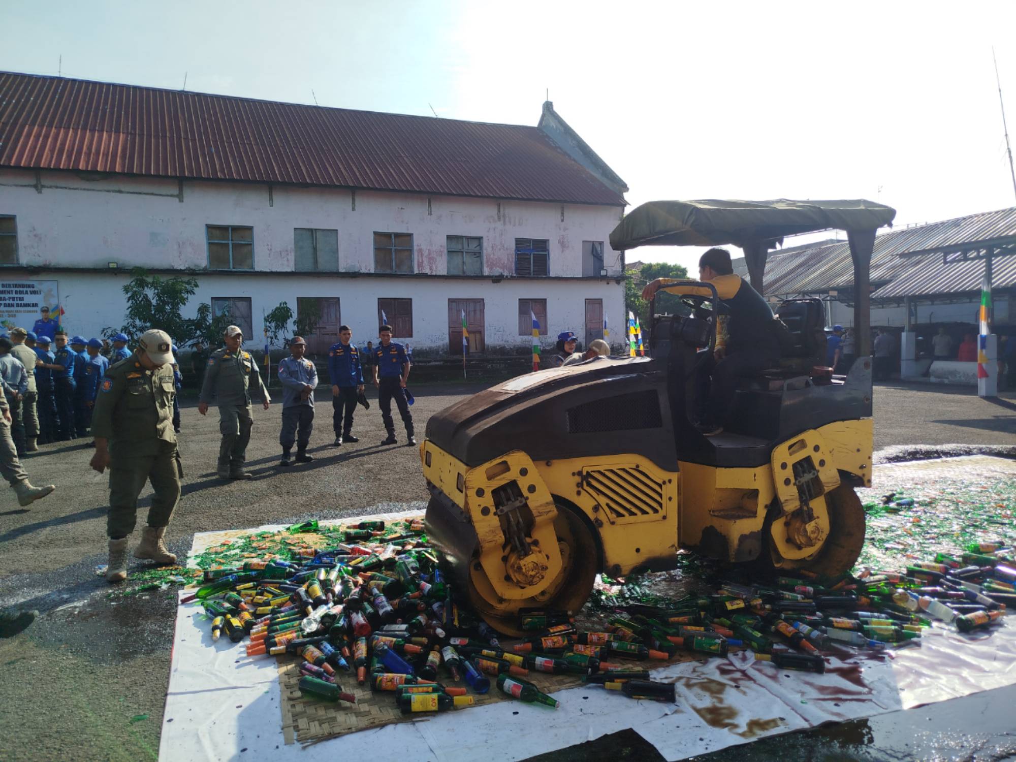 Alat berat melindas botol-botol miras dalam pemusnahan barang bukti oleh Satpol PP dan Damkar Cianjur di halaman kantor Satpol PP.