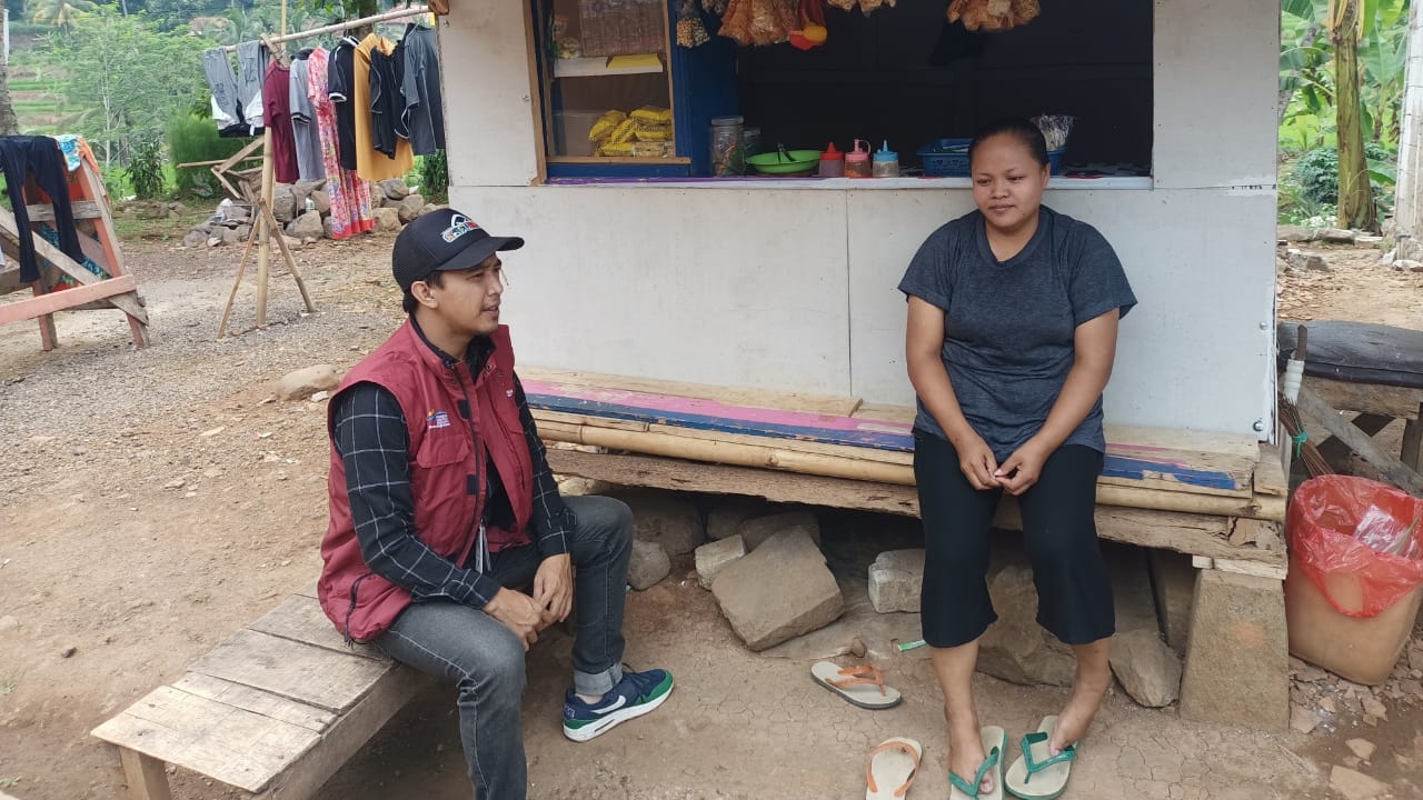 Sandi Wiraguna, pendamping PKH Kemensos Cianjur, berbincang dengan penerima manfaat di depan warung kecil Desa Babakankaret dalam kegiatan pembinaan menuju graduasi mandiri.
