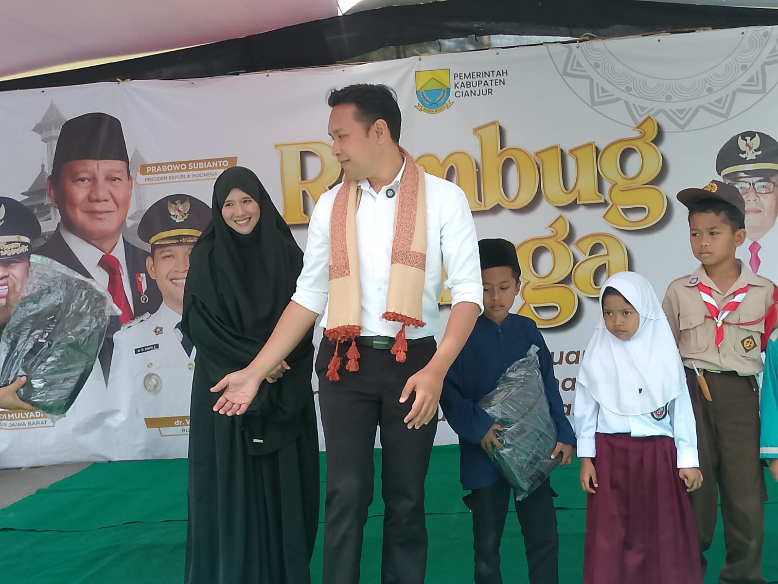Teks: Bupati Cianjur memberikan bantuan perlengkapan sekolah kepada anak-anak saat acara Rembug Warga di Desa Sukawangi.