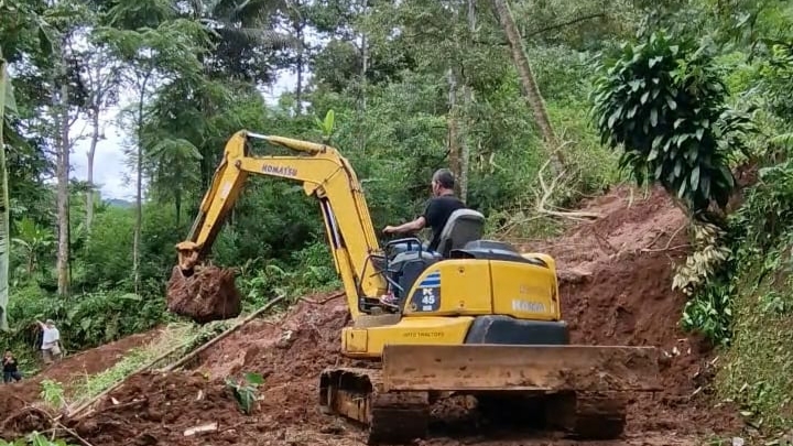 Teks: Alat berat membersihkan material longsor di Jalan Raya Mekarjaya, Kecamatan Mande, Kabupaten Cianjur, Selasa (11 November 2025).