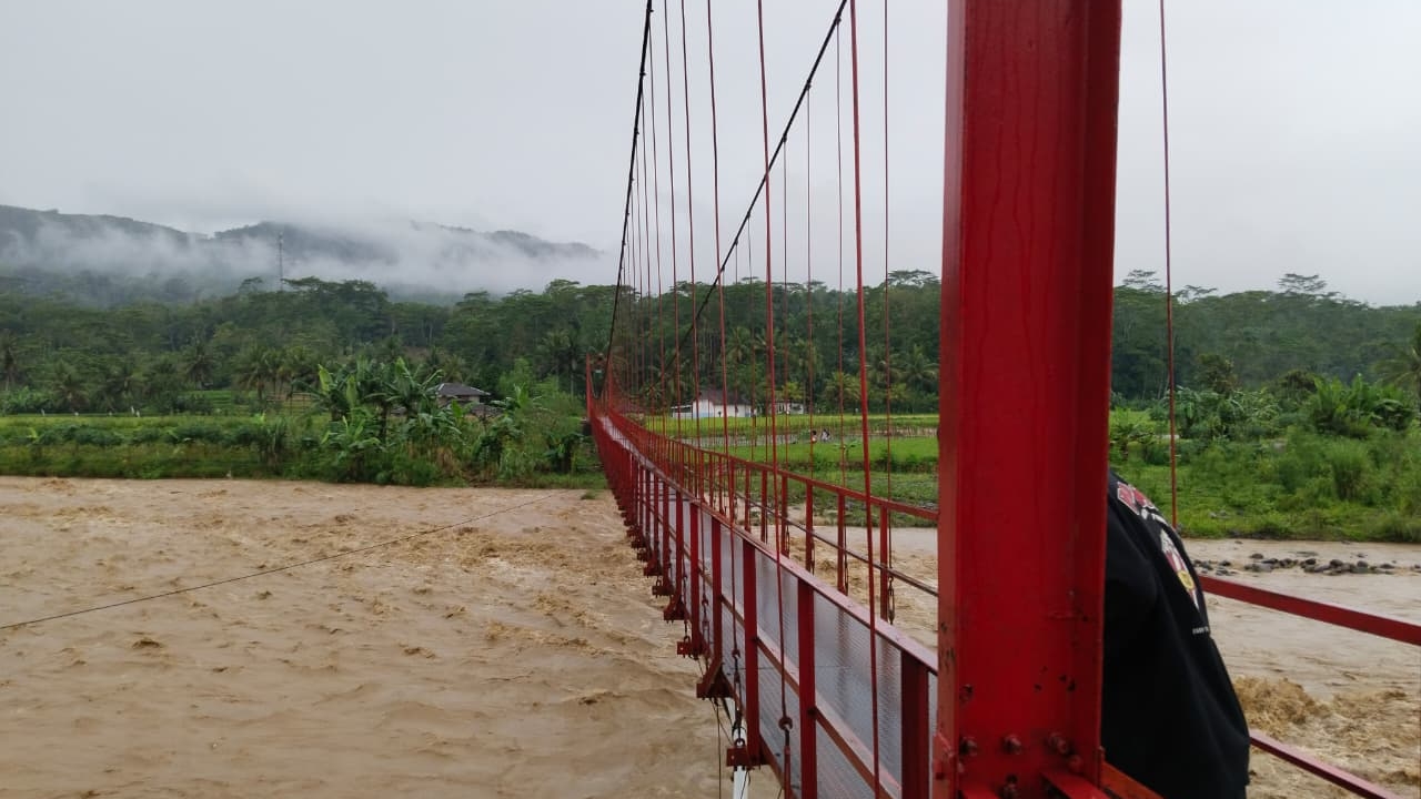 Teks: Jembatan Merah di Desa Pagermaneuh, Kecamatan Tanggeung, Cianjur, sebelum hanyut terbawa arus Sungai Cibuni yang meluap akibat hujan deras. Selasa (11/11/2025). (Dok. Polsek Tanggeung)