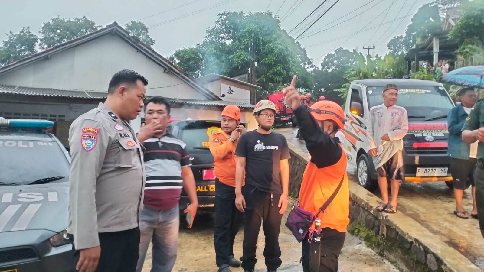 Teks: Anggota Polsek Cikalongkulon dan tim rescue memantau lokasi pencarian anak yang hanyut di Sungai Cikundul.