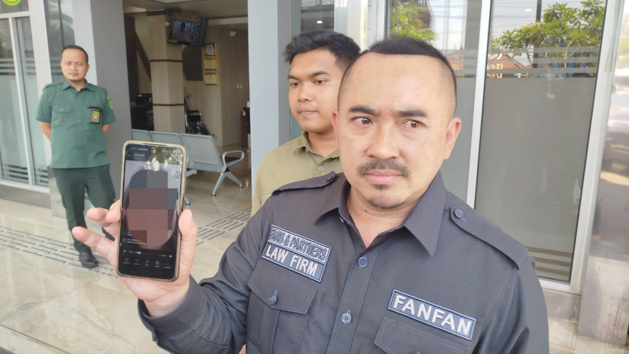 Teks: Fanfan Nugraha memperlihatkan rekaman live TikTok melalui ponselnya saat berada di depan Pengadilan Negeri Cianjur.