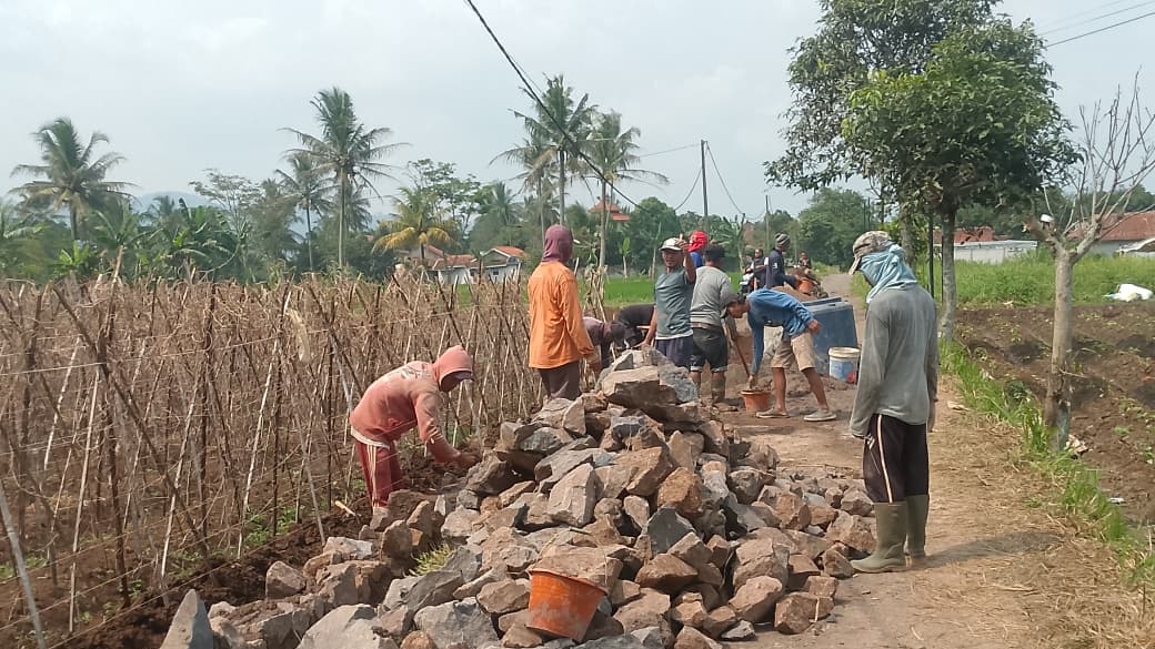 Teks: Pekerja desa membangun Tembok Penahan Tanah di wilayah Kampung Cijurang.