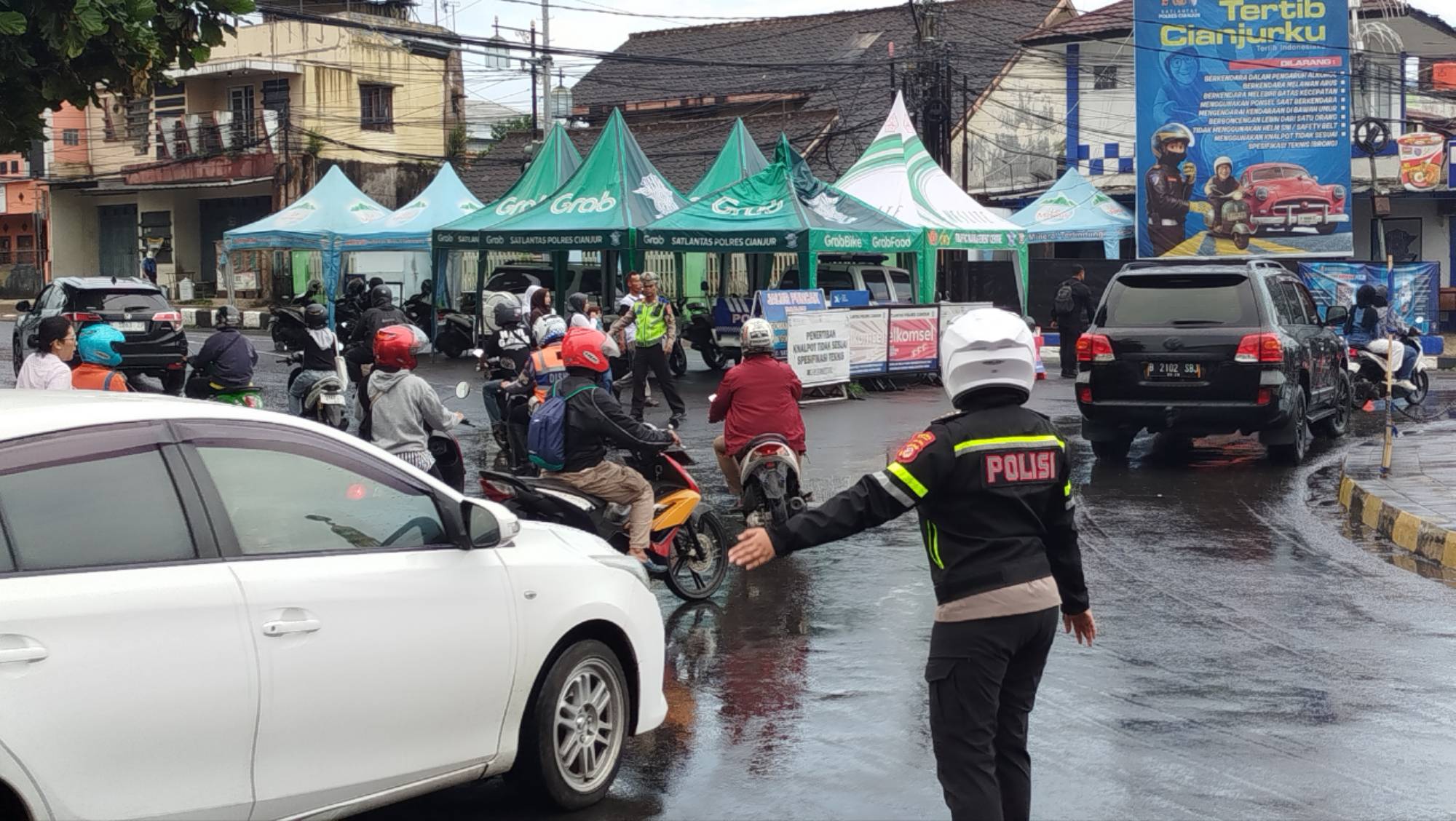 Teks: Petugas Satlantas Polres Cianjur mengatur arus lalu lintas jelang Natal 2025 dan Tahun Baru 2026 di Bundaran Citimall Cianjur.