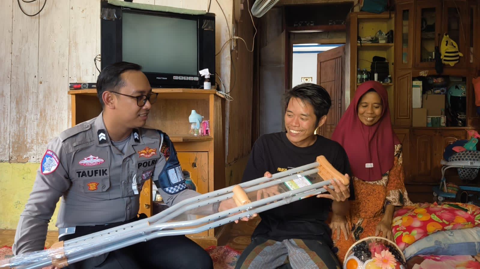 Teks: Polisi memberikan kruk kepada korban kecelakaan lalu lintas saat menjenguk di rumah korban di Cianjur.