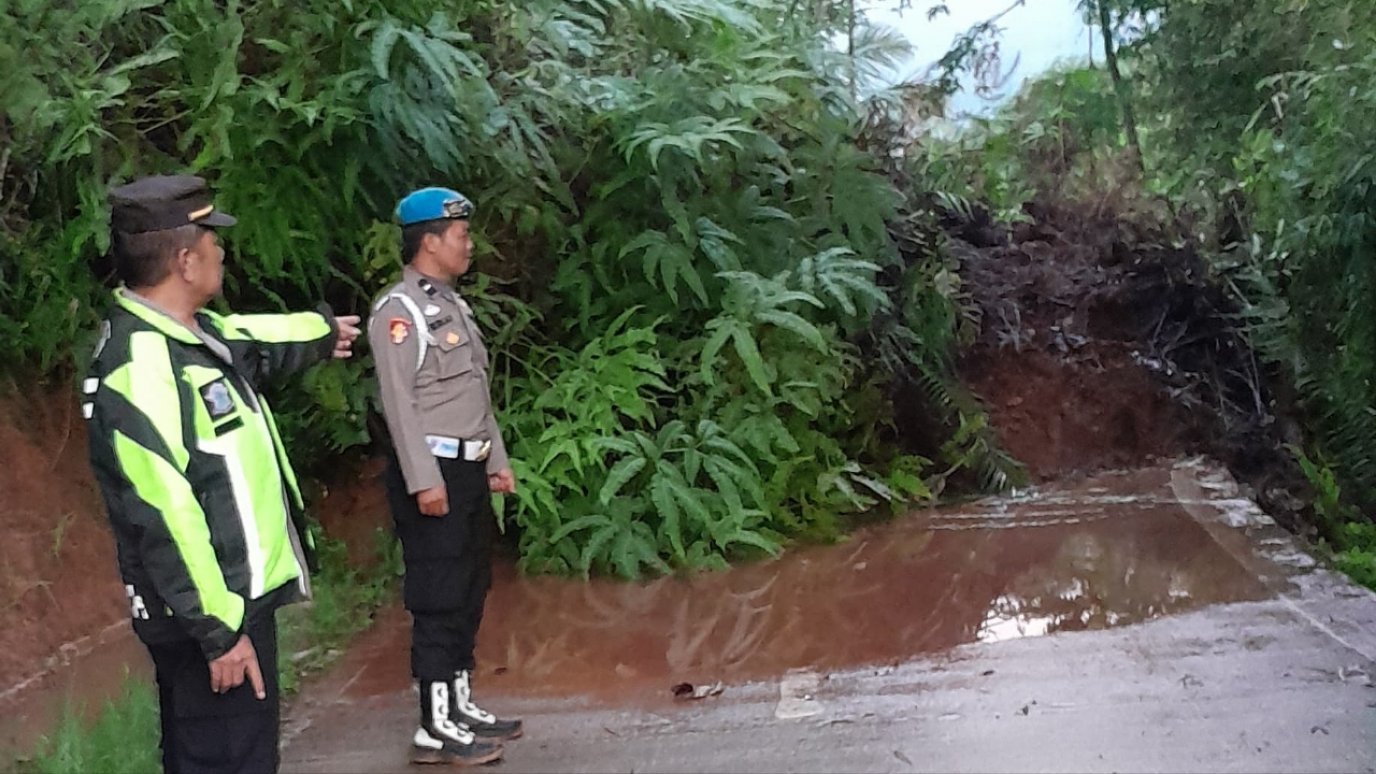 Teks: Petugas mengecek lokasi longsor Campakawarna yang menutup jalan kabupaten di wilayah Campakamulya Cianjur