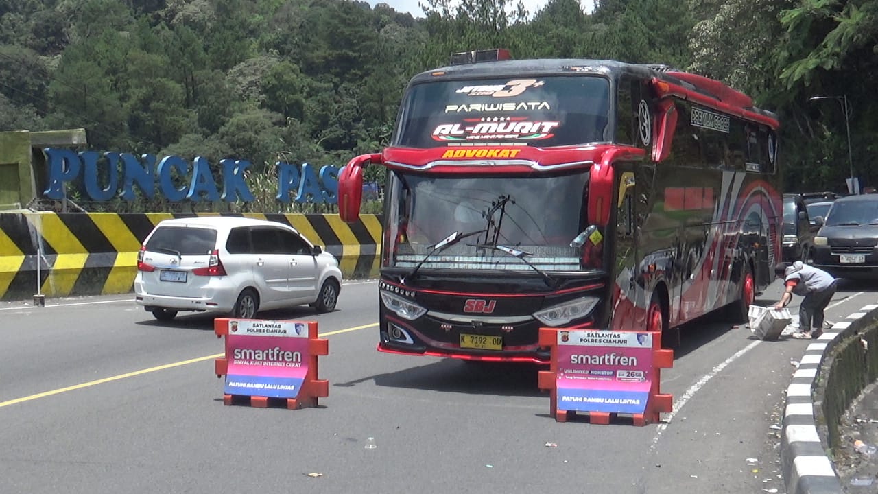 Teks: Petugas polisi mengatur lalu lintas di jalur Puncak Pass Cianjur saat arus kendaraan meningkat
