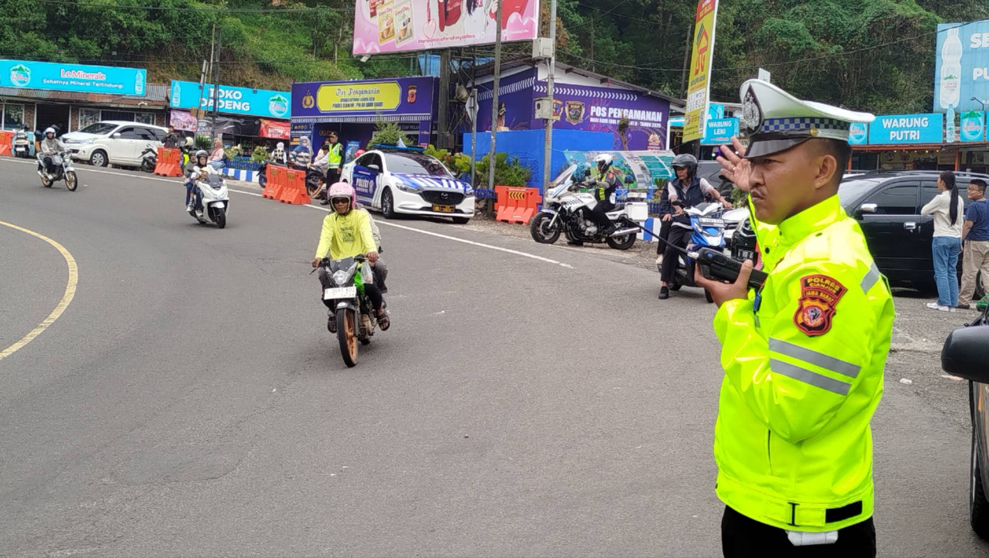 Teks: Petugas kepolisian mengatur arus lalu lintas di jalur Puncak Cianjur saat arus balik Lebaran