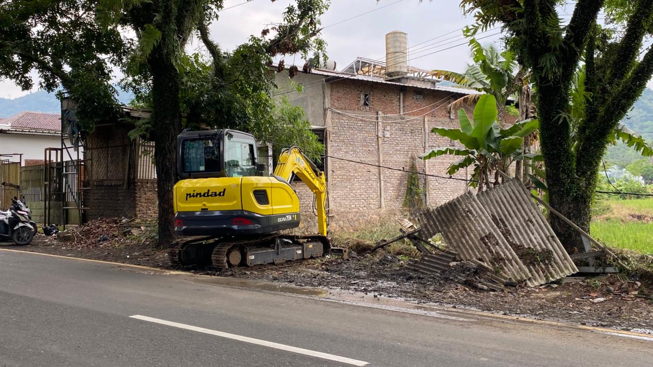 Teks: Ekskavator melakukan pengerukan saluran air di Cibeber Cianjur untuk mengatasi banjir akibat pendangkalan drainase