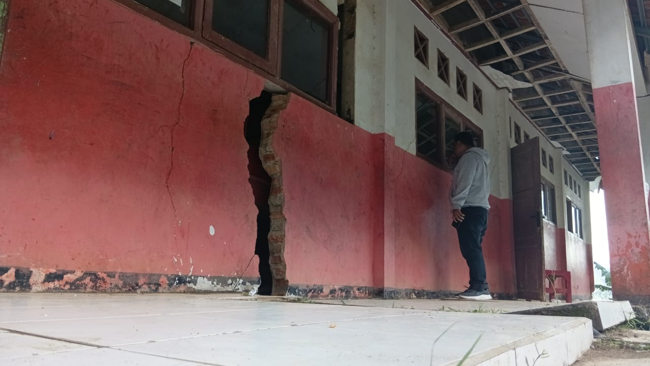 Teks: Jurnalis melihat detail kerusakan dinding retak parah di SDN Karyamukti Campaka