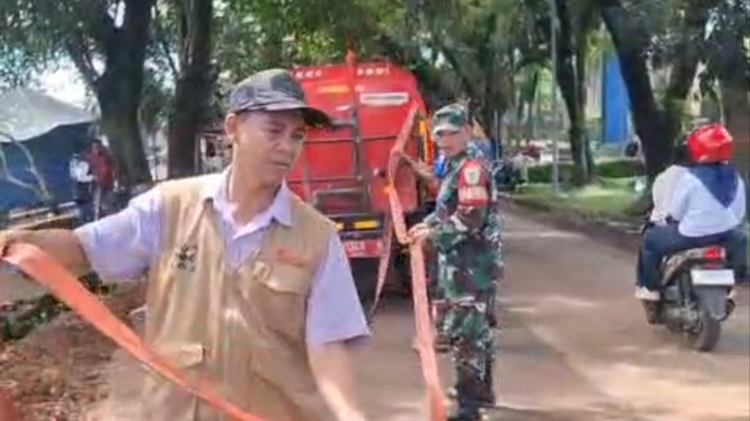 Teks: Camat Mande memantau pembersihan jalan licin akibat galian tanah di Bobojong