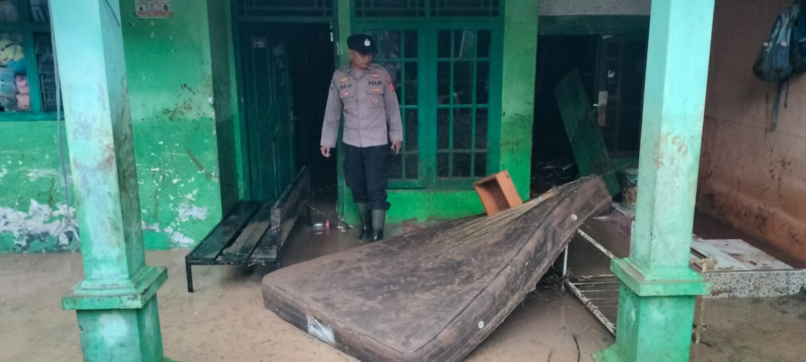 Teks: Petugas Polsek Mande memeriksa rumah warga yang rusak akibat banjir bandang Jamali di Cianjur
