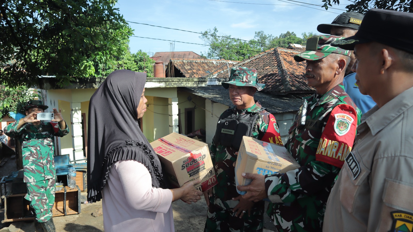 Teks: TNI Kodim 0608 Cianjur menyerahkan bantuan sembako kepada warga terdampak banjir bandang Jamali