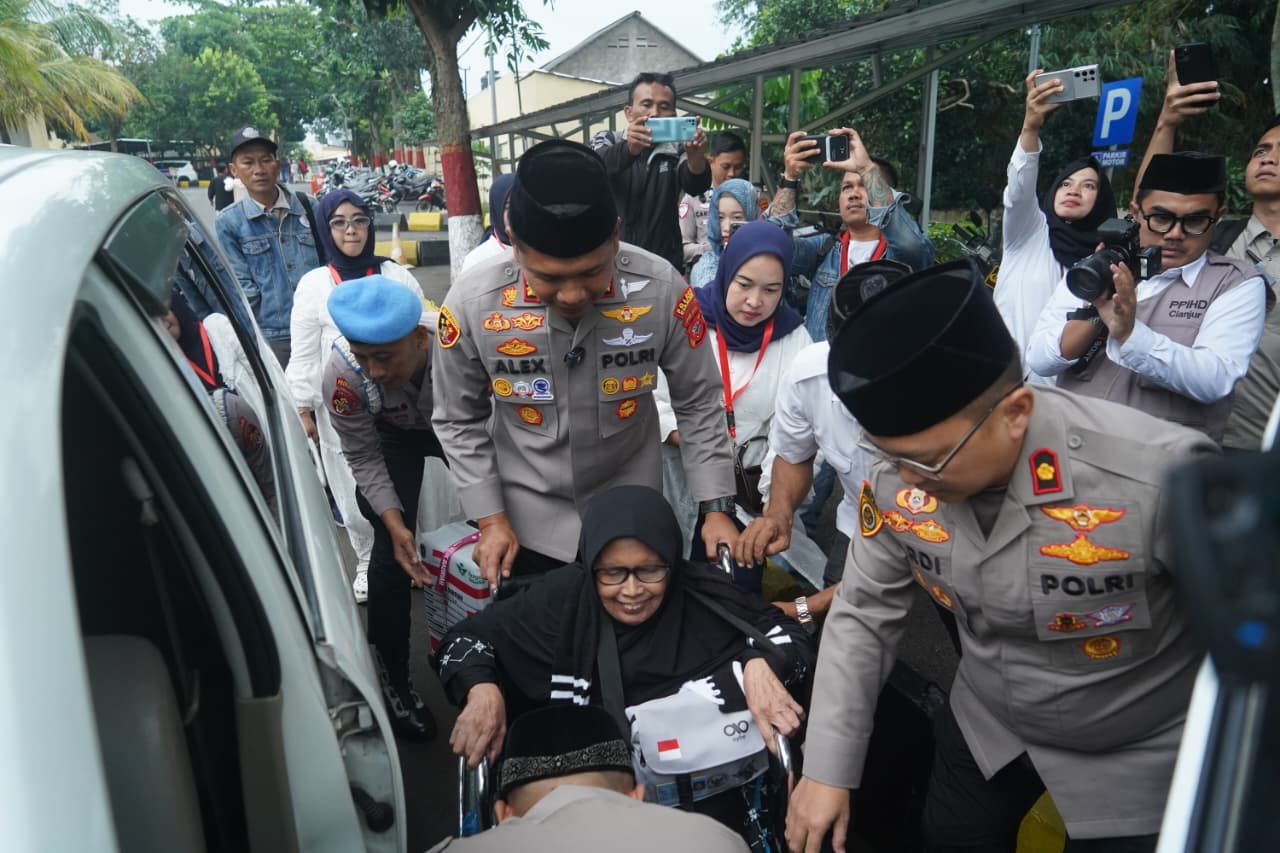 Teks: Kapolres Cianjur mendampingi jemaah haji lansia menggunakan kursi roda di Mapolres Cianjur.