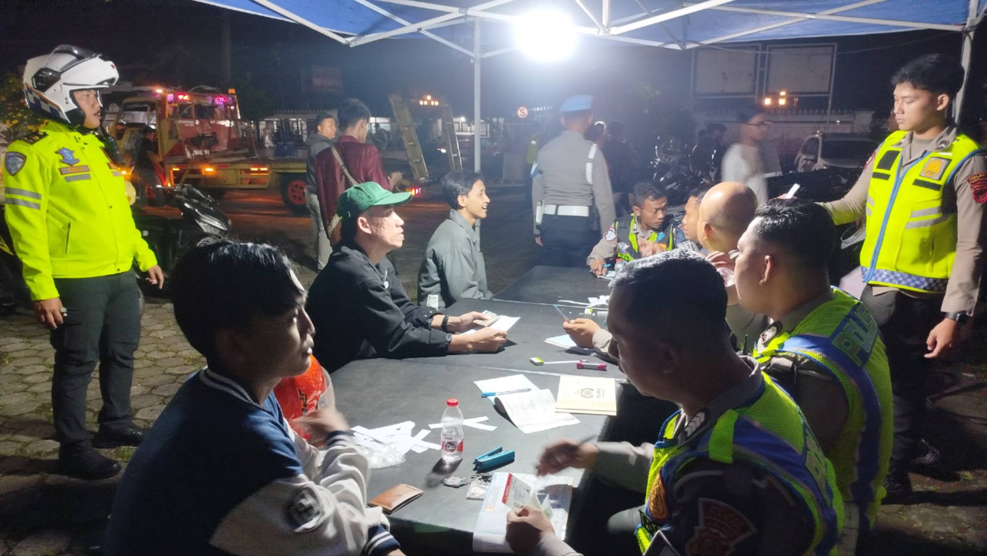 Teks: Petugas polisi memeriksa pengendara dan mendata pelanggaran dalam razia knalpot brong di Cianjur.