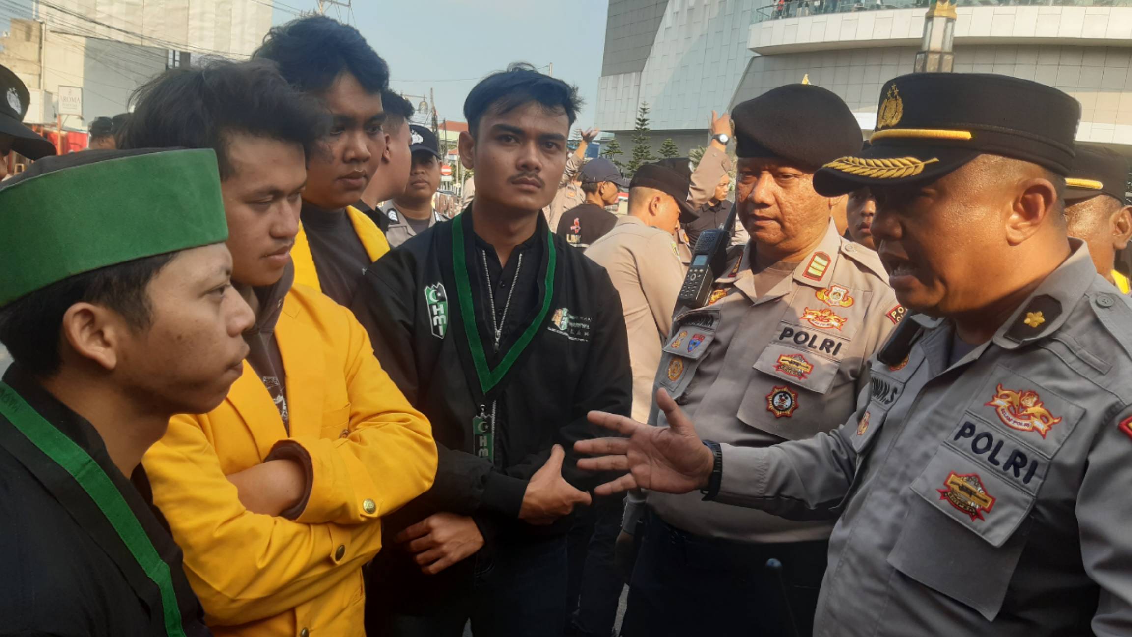 Teks: Aparat Polres Cianjur berdialog dengan mahasiswa yang menutup akses jalan nasional saat aksi unjuk rasa di Bundaran Tugu Tauhid hingga memicu kemacetan kendaraan.
