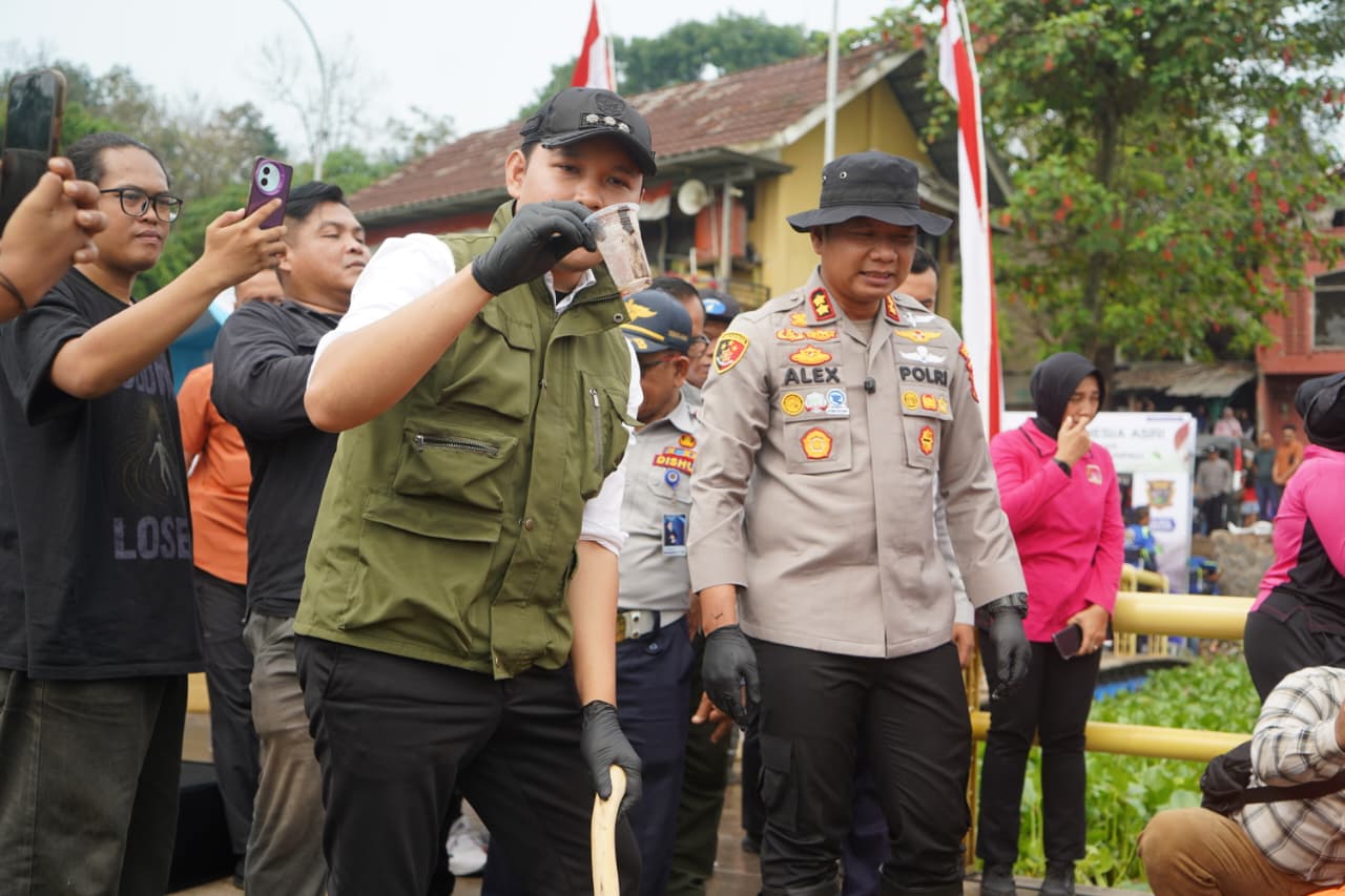 Teks: Bupati Cianjur mengambil sampah plastik dari Danau Jangari saat aksi bersih lingkungan bersama Polres Cianjur.
