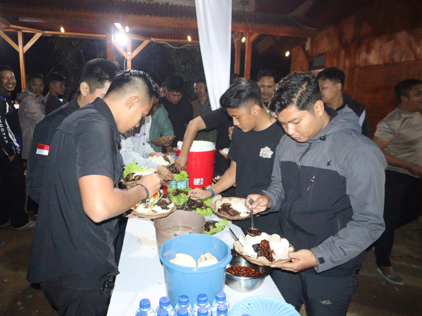 Teks: Personel Polres Cianjur makan malam bersama di Curug Citambur sebagai bagian dari persiapan menghadiri pembukaan TMMD Kodim 0608/Cianjur di Kecamatan Cibinong.