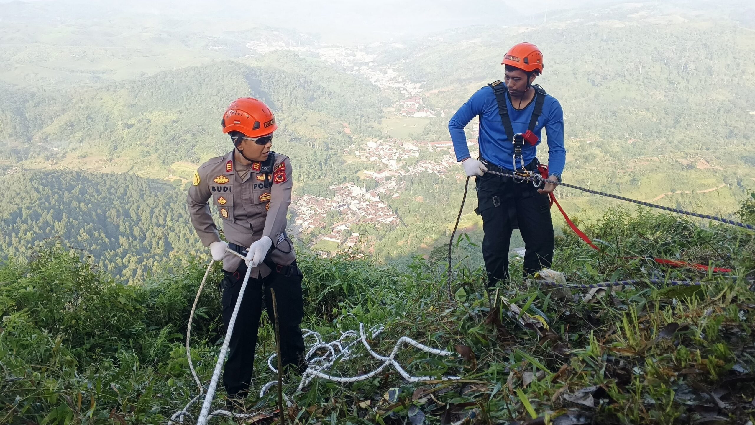 Teks: Kapolsek Pagelaran AKP Budi Rustandi turun langsung dalam kegiatan pembentangan spanduk HUT Bhayangkara ke-80 di Gunung Karang Cianjur.