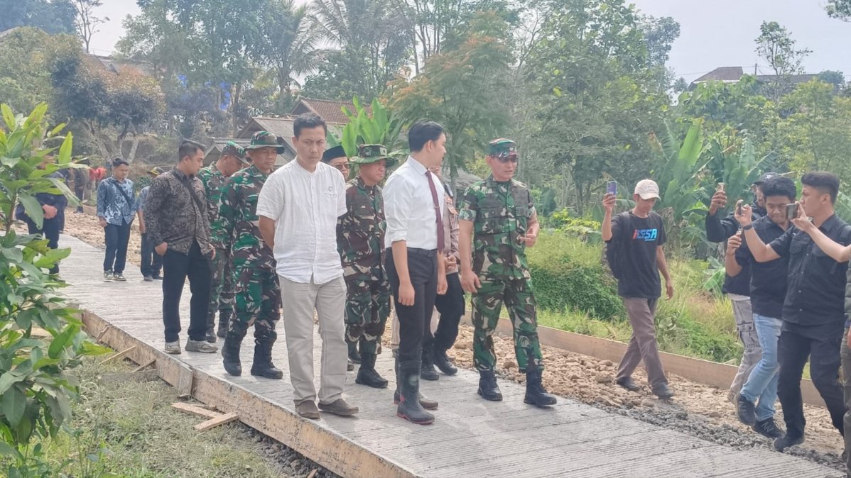 Teks: Pekerjaan pembangunan Jalan Mekarsari melalui program TMMD di Desa Mekarsari, Kecamatan Cibinong, Kabupaten Cianjur.