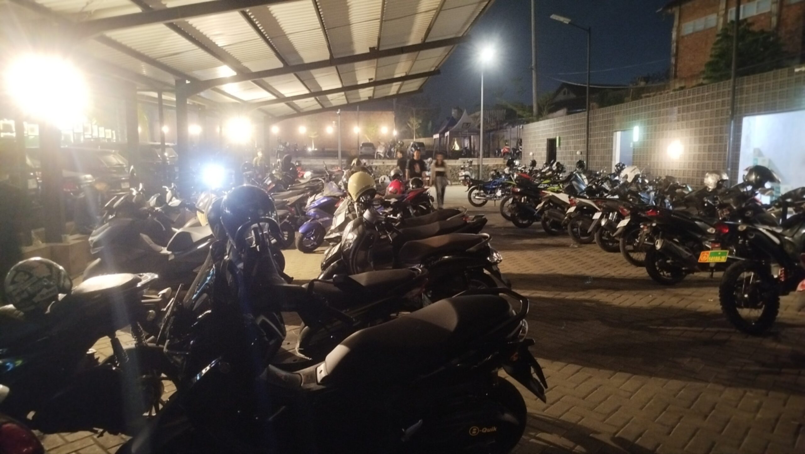 Teks: Suasana parkiran Cafe Nako pada malam hari yang dipenuhi sepeda motor pengunjung.