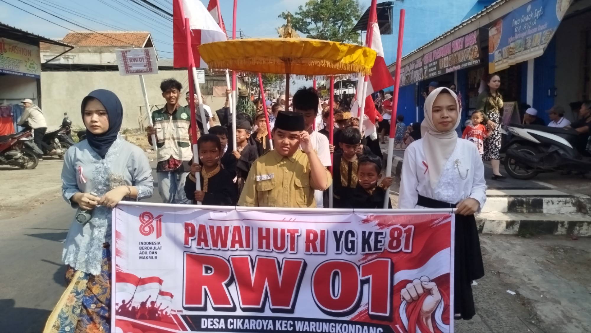 Teks: Peserta RW 01 Desa Cikaroya mengikuti pawai HUT RI ke-81 di Kecamatan Warungkondang.