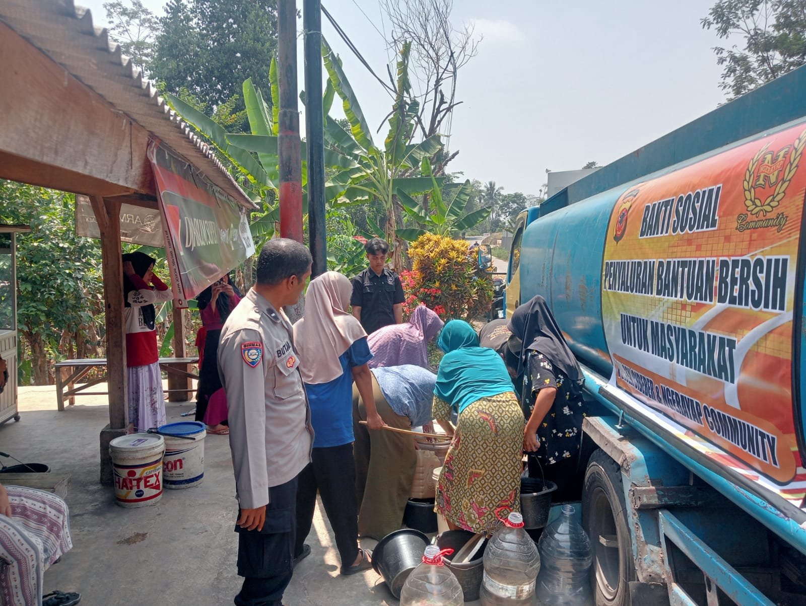 Teks: Polres Cianjur dan Ngerayap Community menyalurkan 8.000 liter air bersih kepada warga Cimanggu terdampak kekeringan.
