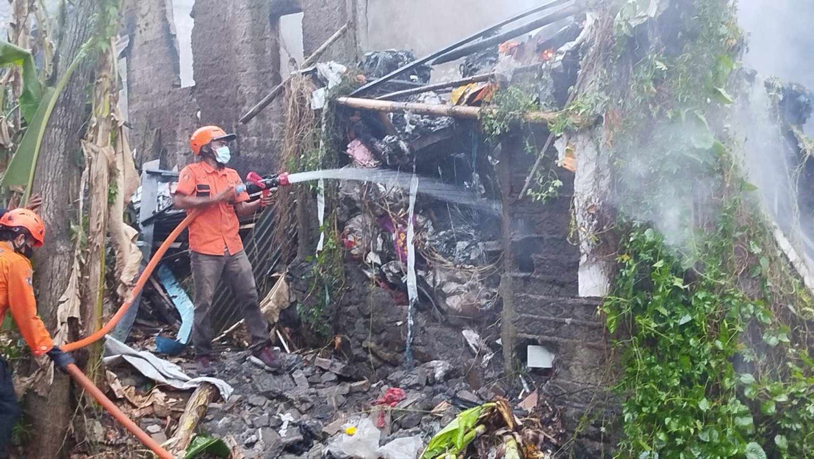 Teks: Petugas pemadam kebakaran melakukan pendinginan di lokasi kebakaran dua rumah di Joglo Cianjur.