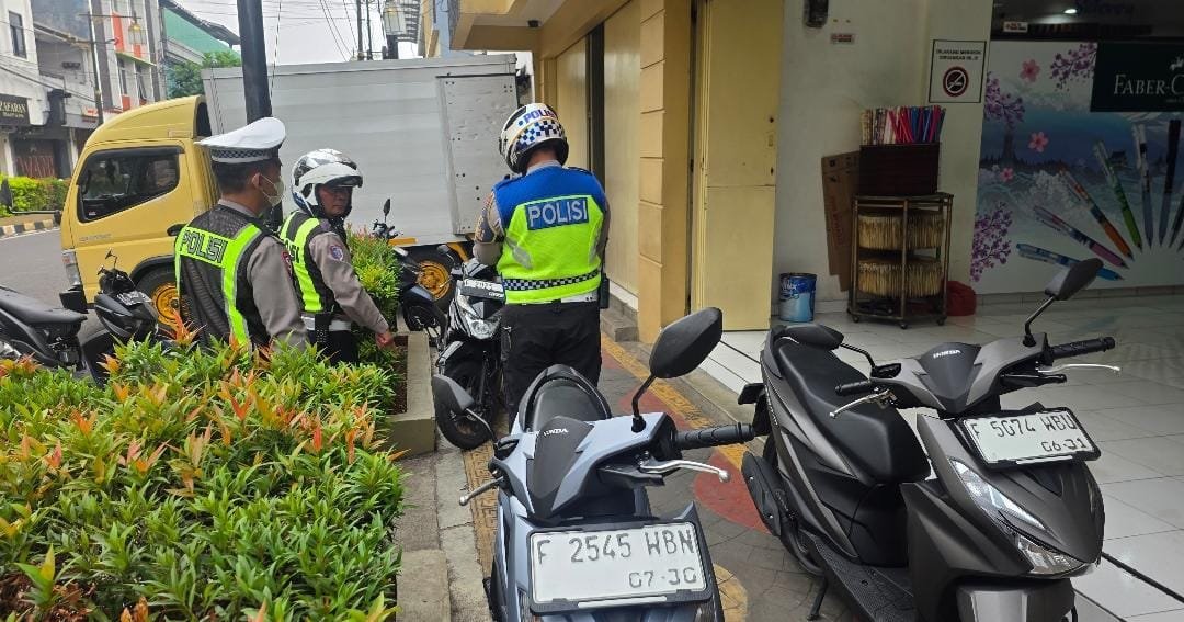 Teks: Petugas Satlantas Polres Cianjur memeriksa kendaraan yang terparkir di trotoar pejalan kaki saat Hunting ETLE.