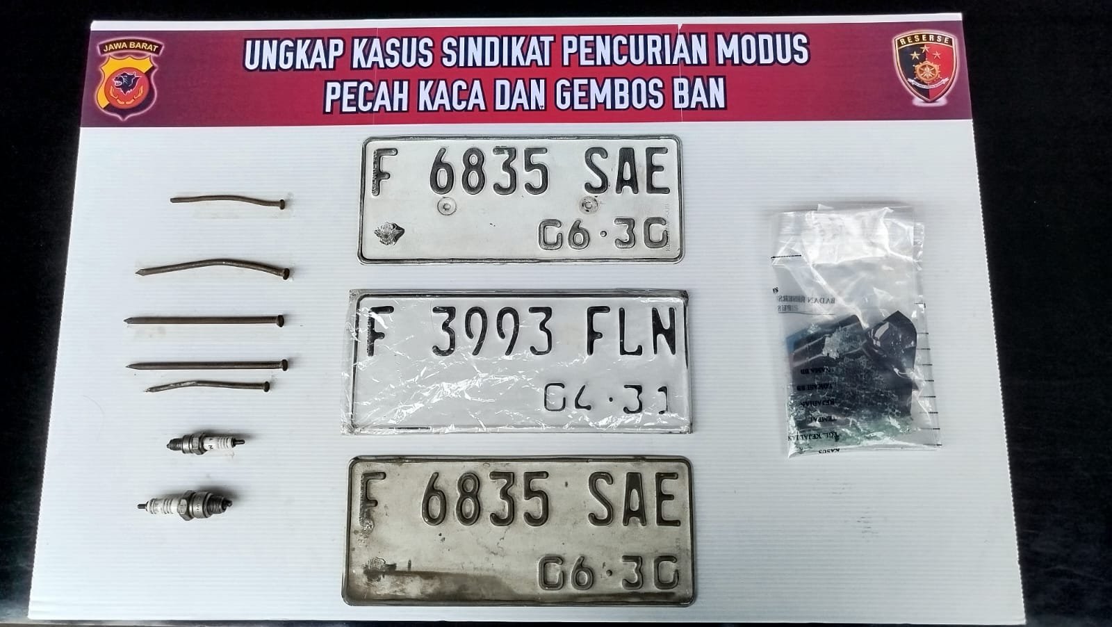 Teks: Barang bukti paku, busi, dan pelat nomor kendaraan dalam kasus pencurian bermodus pecah kaca dan gembos ban di Cianjur.