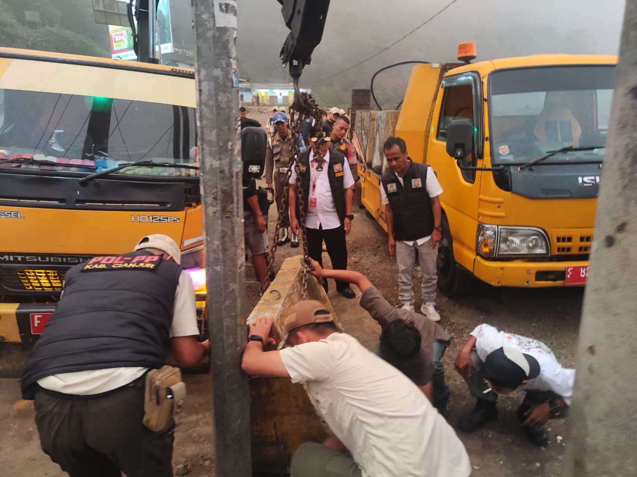 Teks: Satpol PP Cianjur memasang pembatas beton di Rest Area Segar Alam Puncak untuk mencegah PKL kembali berjualan.